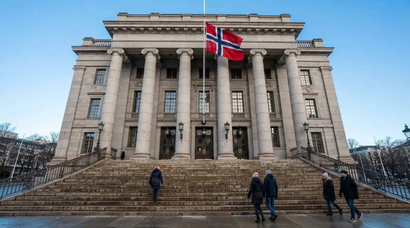 Fasade av en stor offentlig bygning i Oslo med brede trapper og et norsk flagg i vinden under klar himmel